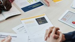 Team members discuss data reports and statistics in a collaborative setting around a table.