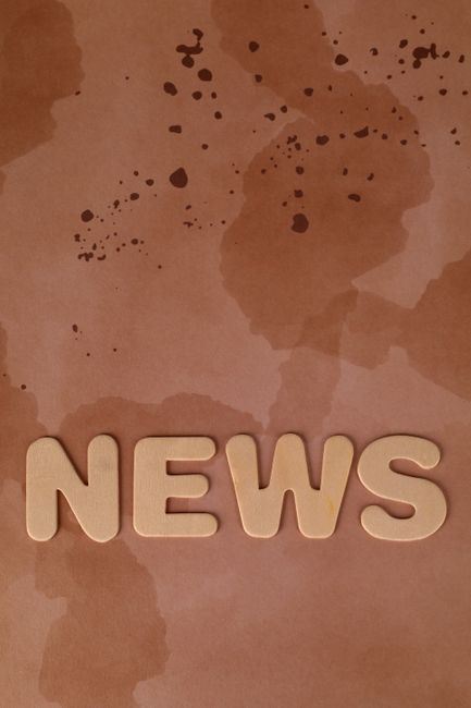 Artistic photo of 'NEWS' letters on a coffee-stained background, perfect for media-related content.
