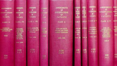 A row of red hardcover books titled 'Abridgments of Specifications of Patents'.