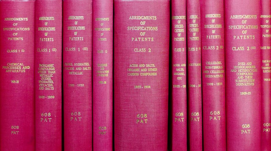 A row of red hardcover books titled 'Abridgments of Specifications of Patents'.